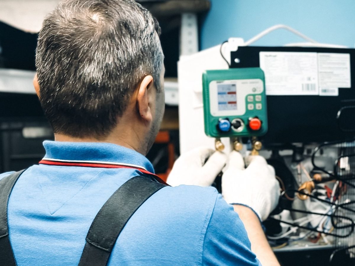 Técnico medindo a pressão de um sistema de climatização com manifold